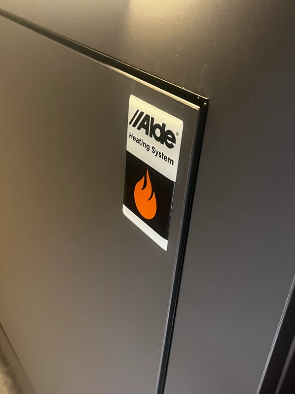 Alde Heating System domedekal med orange flamma monterad på värmepanel